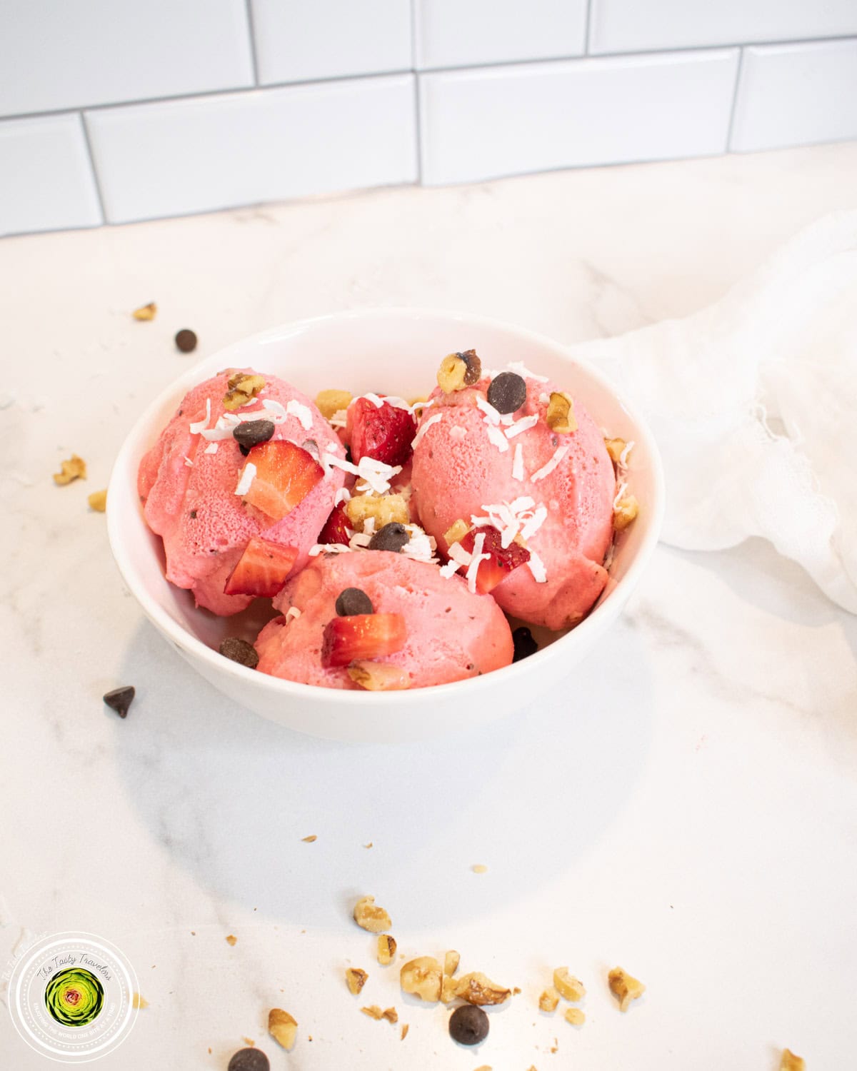 Bowl of Ninja Creami strawberry coco-nut protein ice cream topped with walnuts and coconut