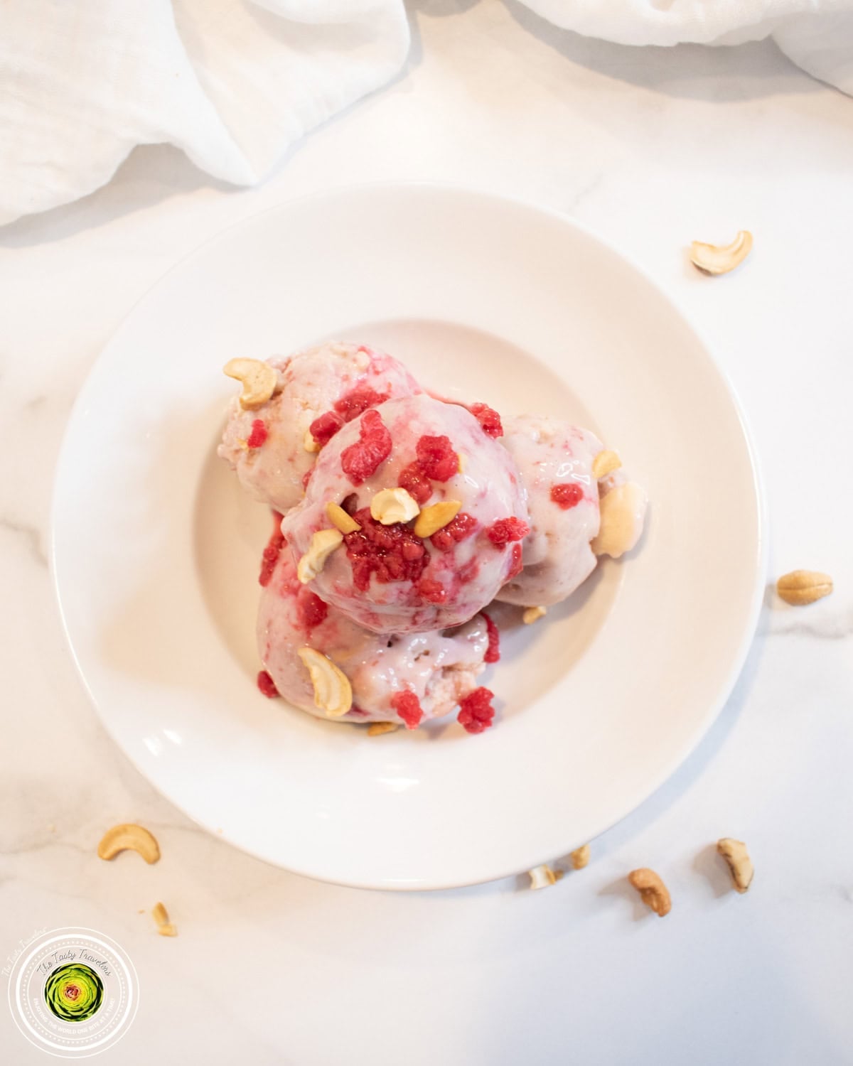 Ninja Creami baseball nut protein ice cream in a pint container with cashews and raspberry sauce