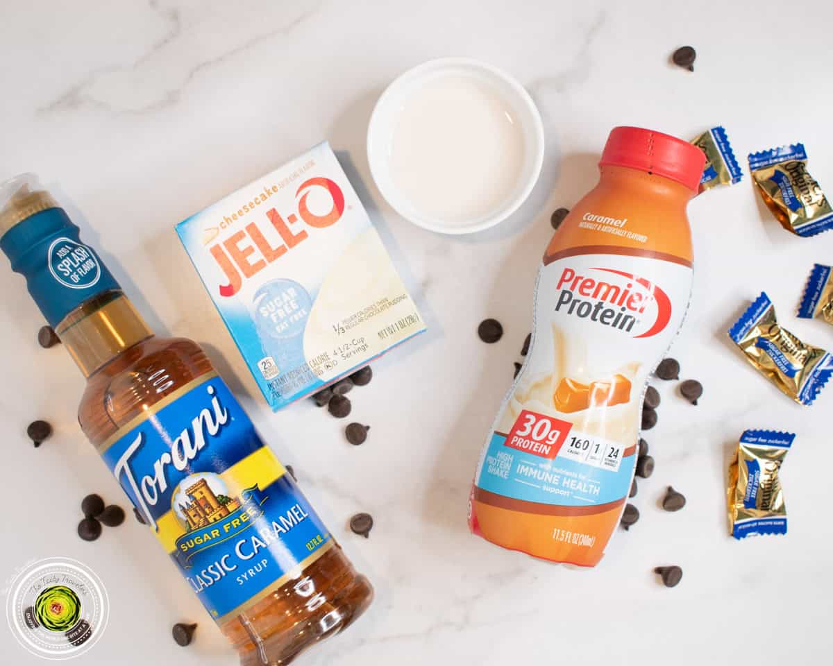 Ingredients for Ninja Creami caramel chocolate chip cheesecake protein ice cream including caramel protein shake, cheesecake pudding mix, chocolate chips, and Werther's candies
