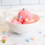 Delicious pink ice cream with candy toppings in a white bowl, perfect for dessert lovers.