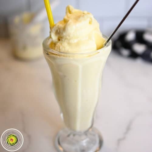 Creamy vanilla milkshake in a tall glass with a yellow straw.
