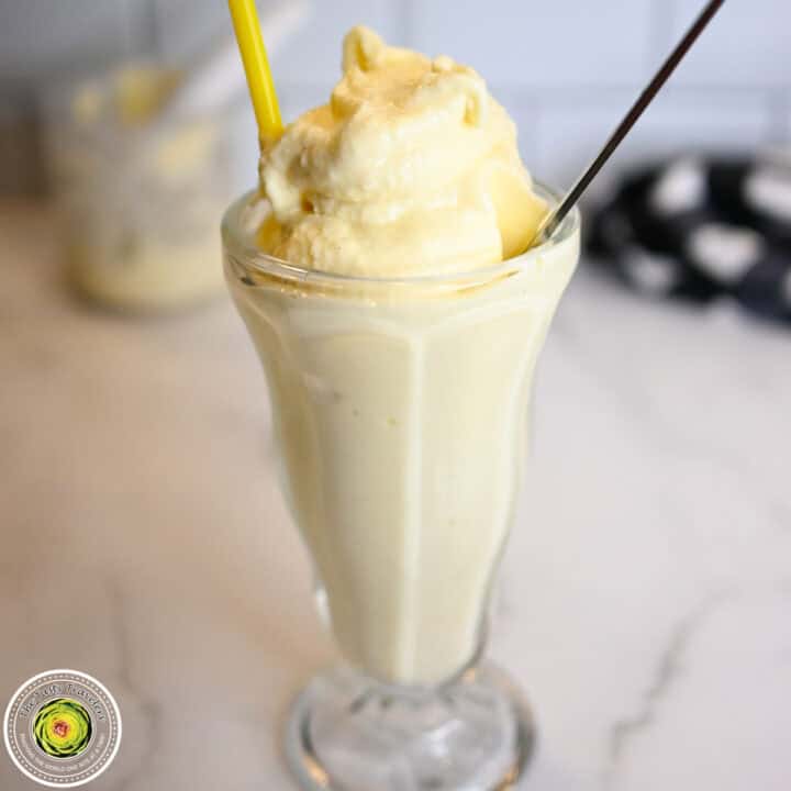 Creamy vanilla milkshake in a tall glass with a yellow straw.