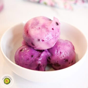 Close-up of three purple ice cream scoops in a white bowl.